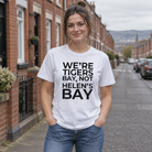 Woman wearing the white We're Tigers Bay, Not Helen's Bay tee on a red brick street in North Belfast
