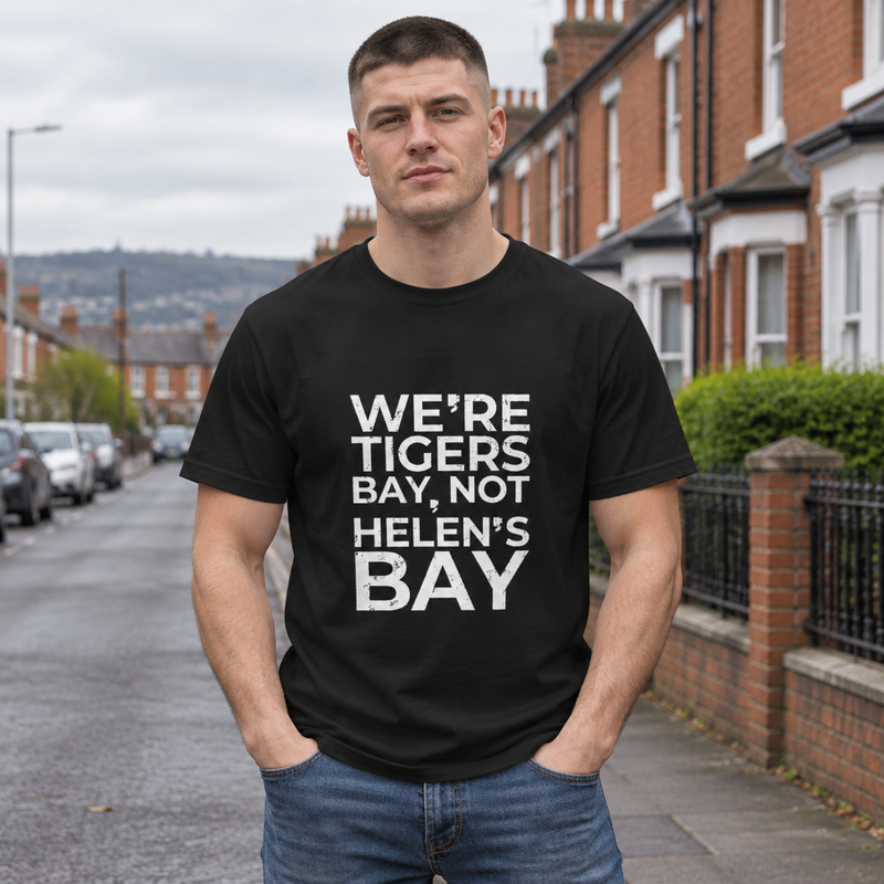 Man wearing the black We're Tigers Bay, Not Helen's Bay tee on a red brick street in North Belfast