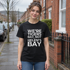 Woman wearing the black We're Tigers Bay, Not Helen's Bay tee on a red brick street in North Belfast